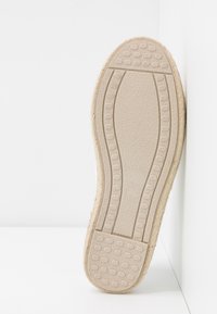 Beige podrážka s texturovaným povrchem a kruhovými vzory pro lepší přilnavost. Hladký povrch, zaoblený tvar, minimální detaily. Okraj doplněný přírodní vlákninou.