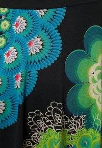 Tissu avec des motifs floraux éclatants en bleu, vert, blanc et rose sur fond noir, présentant des motifs compliqués de pétales et de dentelle.