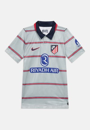 Szary jersey piłkarski z czerwonymi i granatowymi poziomymi paskami, granatowym kołnierzem, herbem Atletico Madryt, logo Nike oraz logo sponsora Riyadh Air.
