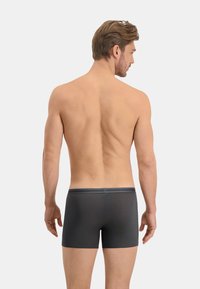 Boxers gris en tissu lisse, avec une taille douce et un design minimaliste, vus de dos sur un fond neutre.
