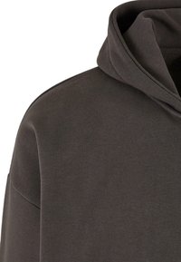 Dark gray hoodie featuring a textured fabric, a relaxed fit, and a large, soft hood design. Seam detailing visible along the shoulders.