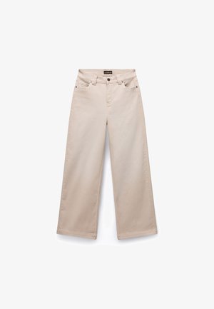 Beige wijde broek van katoen met een gladde textuur. Beschikt over vijf zakken, riemlussen en zilverkleurige hardware aan de voorkant.