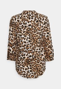 Blusa com padrão de leopardo, apresentando uma mistura de cores castanho, preto e branco, com mangas três quartos e uma bainha arredondada. Textura suave.