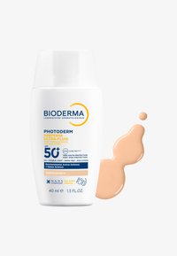 Bioderma Photoderm XDefense Ultra-Fluid SPF 50+, flacone bianco, 40 ml. Contiene un fluido beige chiaro con una texture liscia, che gocciola accanto al flacone.