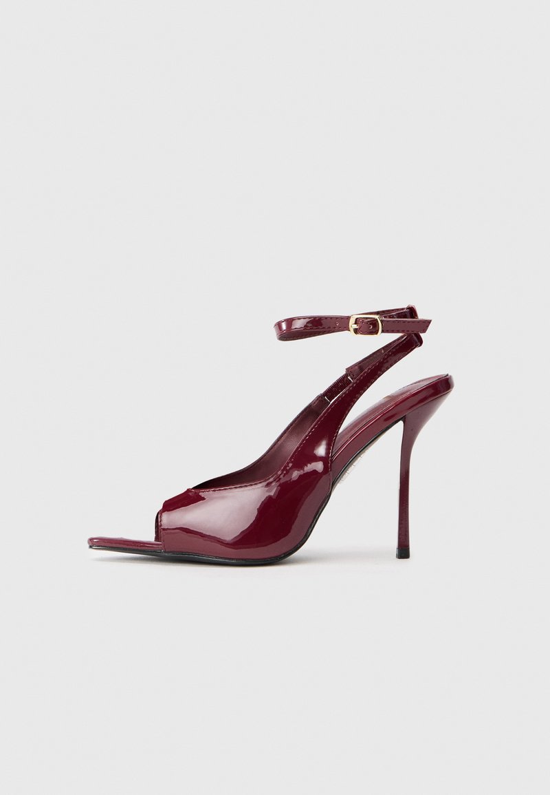 Burgundijas krāsas patentētas ādas sēdeklis ar atvērtu purngalu, potītes siksniņu un elegantu stiletto papēdi. Gluda, spīdīga tekstūra.