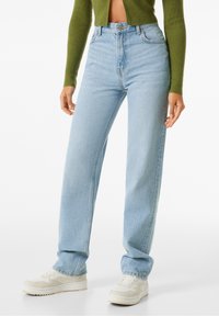 Ljusblå jeans med hög midja och avslappnad passform, klassisk femficksdesign och synliga söm detaljer, kombinerat med vita sneakers.