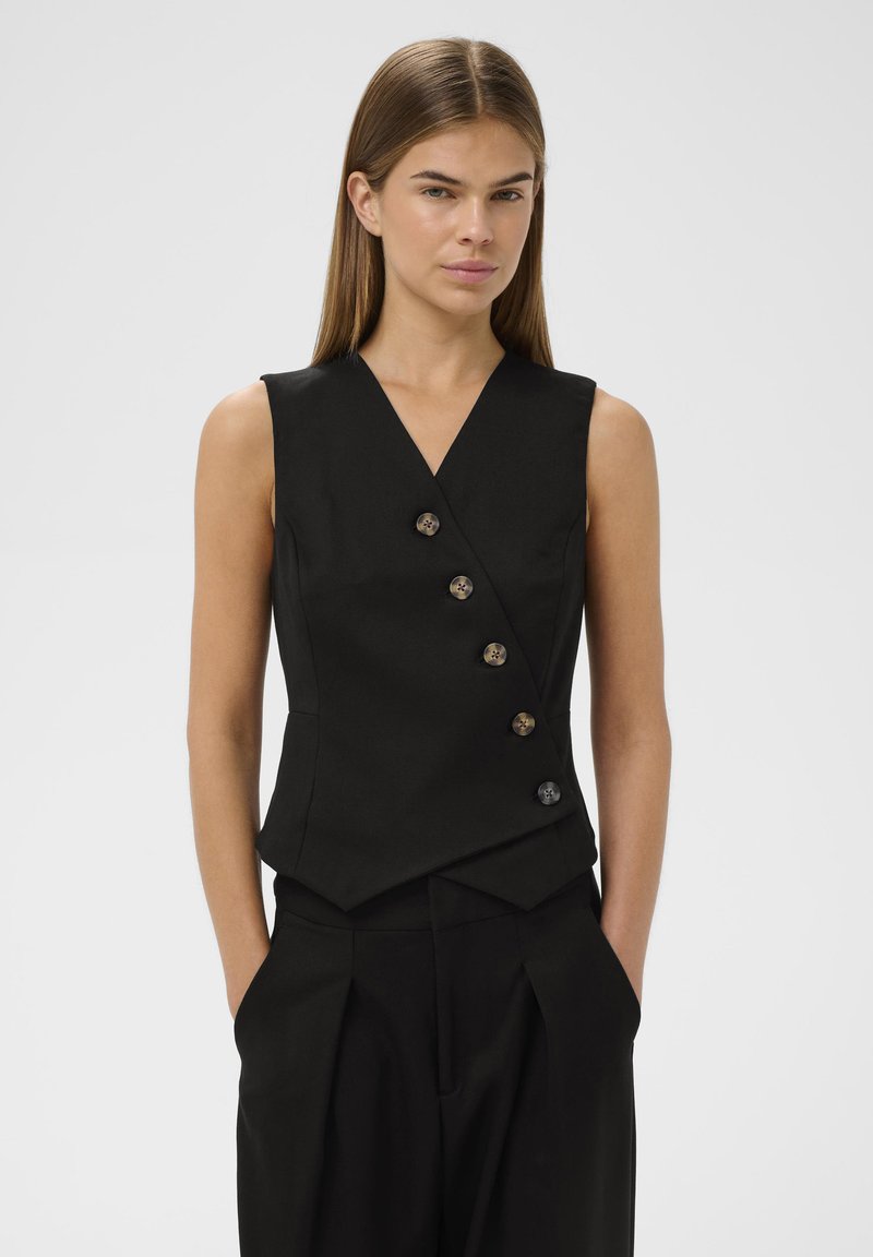 Črn brezrokavnik z V-izrezom, ki ima šest gumbov v kontrastni barvi, prilegajoč kroj in kotahem linijo. Gladka tekstura tkanine.