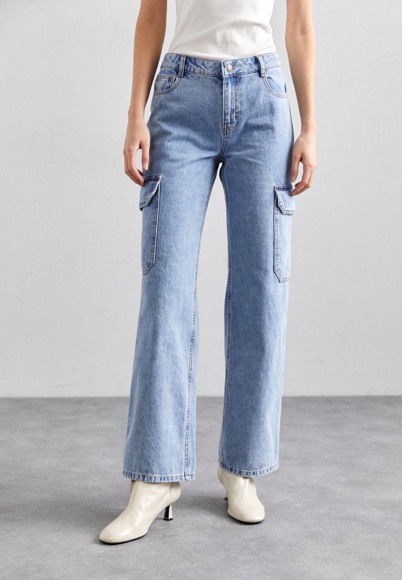 Lys blå vide cargo-jeans med to sidelommer, laget av denim. Har høy midje og en lett falmet utseende.