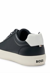 Navy leather sneaker with a white heel tab, round laces, and a textured finish. Features logo on the heel and a contrasting sole.