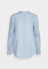 Chemise bleu clair à manches longues avec col mandarin et patte de boutonnage cachée, présentée sur un fond uni.