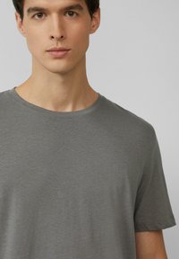 Szary krótki rękaw t-shirt z miękkiego materiału, z okrągłym dekoltem i luźnym krojem. Gładka struktura, minimalne detale szwów.