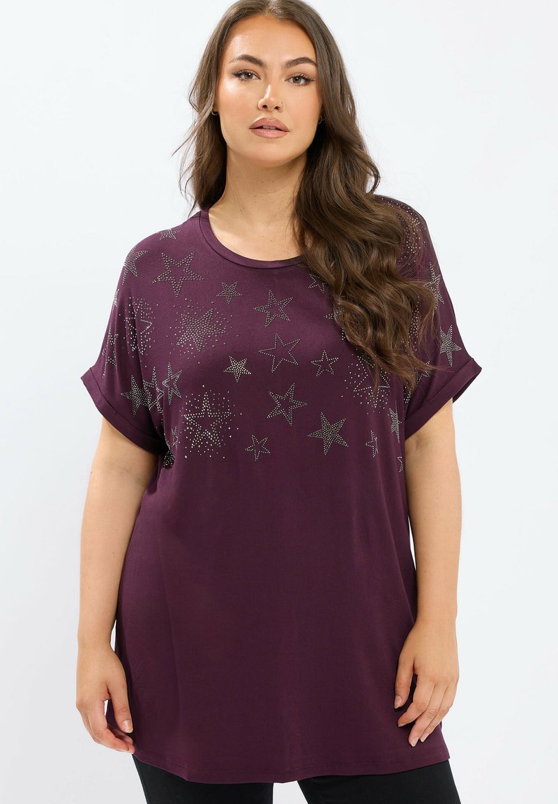 Fioletowy, oversize t-shirt z krótkimi, podwiniętymi rękawami, zdobiony metalicznymi gwiazdkami oraz gładką fakturą materiału.