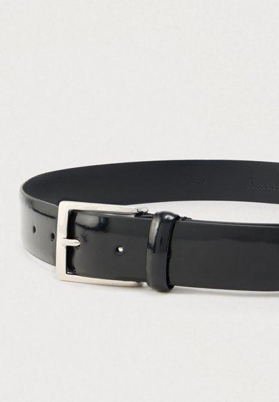 Sort læderbælte med en skinnende finish, der har en rektangulær sølvfarvet metalspænde og fem huller til justering af størrelsen.