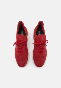 Sneakers rossi con tomaia in maglia traspirante, lacci abbinati e suola liscia. Presentano un logo rotondo e motivi testurizzati sulla superficie.