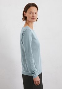 Helles blaues Sweatshirt aus weichem Stoff, mit langen Ärmeln, rundem Halsausschnitt und gerippten Bündchen sowie Saum. Glatte Textur mit minimalen Details.