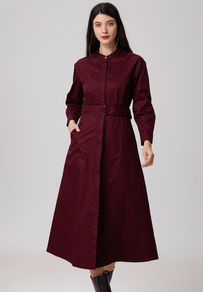 Robe à manches longues bordeaux avec des boutons, dotée d'une taille ceinturée, de poches latérales et d'une silhouette évasée. Matériau en coton doux.