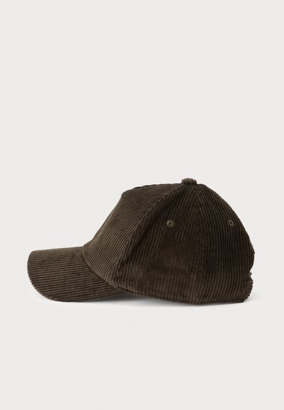 Casquette de baseball en velours côtelé marron avec une visière courbée sur un fond clair uni, vue de profil.