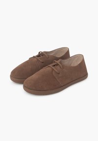 Scarpe in suede marrone con una superficie morbida, punta rotonda e suola piatta in gomma. Presentano una chiusura con lacci e due occhielli sulla parte anteriore.