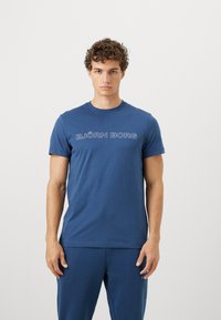 Μπλε κοντομάνικο μπλουζάκι από μαλακό βαμβάκι, με λευκό λογότυπο "BJÖRN BORG" κατά μήκος του στήθους. Απλός σχεδιασμός με στρογγυλή λαιμόκοψη.