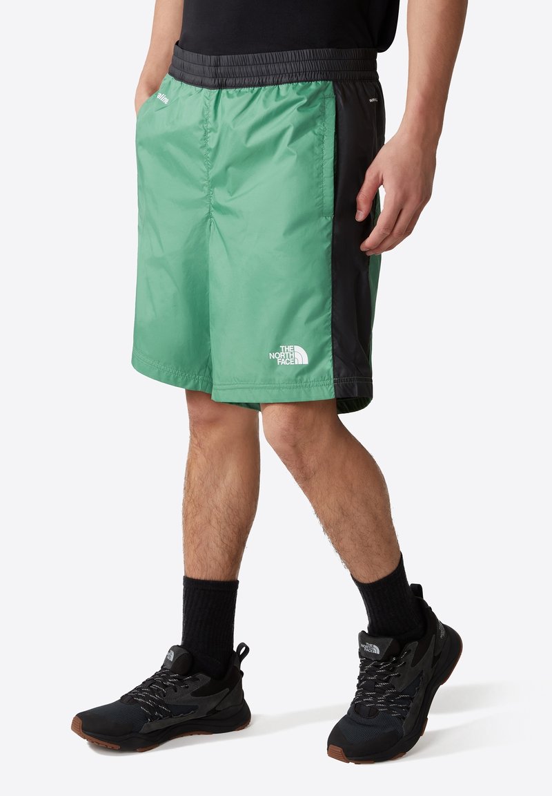 Shorts légers, vert menthe et noirs avec une taille élastique. Comprend des poches et un petit logo blanc en bas à gauche.