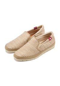 Scarpe slip-on beige chiaro con texture intrecciata, dettagli elastici sui lati e suola in fibra naturale. Presentano un piccolo accento di logo rosso.
