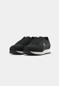 Black sneakers with a smooth fabric upper, white midsole, and black rubber outsole. Features classic lace-up design and logo accent.