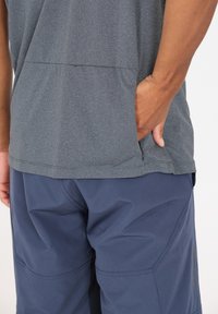 Grå texturerad kortärmad skjorta instoppad i marinblå shorts med fickor; skjortan har en ren design och är tillverkad av ett andningsbart material.