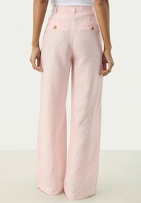 Světle růžové, široké lněné kalhoty s hladkou texturou. Obsahují zadní kapsy s akcenty knoflíků a upravený pas.
