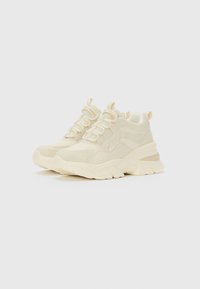 Chunky off-white sneakers with thick textured soles, lace-up fronts, and pull tabs on the tongue and heel, placed angled on a plain background.