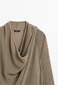 Cardigan beige en tricot avec col drapé et détail froncé à l'épaule, étiqueté Massimo Dutti, présenté sur fond blanc.