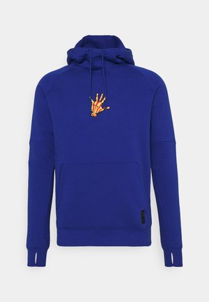 Blå hættetrøje med kængurulomme foran, hul til tommelfingrene på ærmerne og en lille grafik med en gul og rød skeletthånd på brystet.