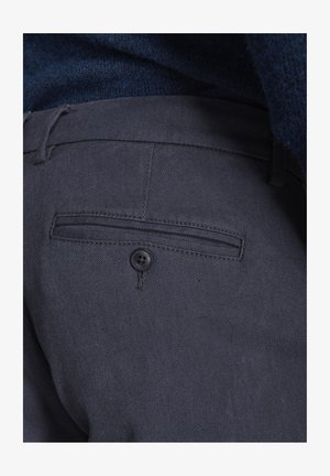 Pantaloni gri închis cu un material texturat, buzunar posterior plat și închidere cu buton negru. Talia include un inel pentru ajustare.