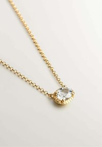 Collar de tono dorado con un colgante ovalado de cristal transparente con un engaste texturizado, montado en una cadena enlazada.