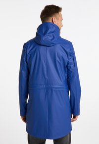 Blå vattentät jacka med huva, långa ärmar, åtsittande midja och slät glänsande yta. Har en elegant design och minimalt med hårdvara.