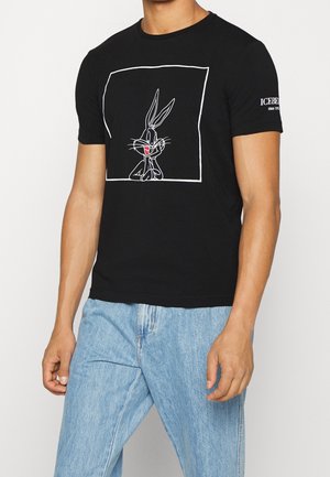 Black cotton t-shirt featuring a white line drawing of a cartoon rabbit in the center, with a printed logo accent on the sleeve.
