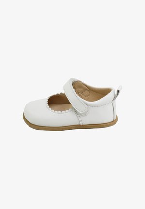 Zapato Mary Jane de cuero blanco con borde ondulado y correa ajustable, que cuenta con un interior suave y una ligera suela de goma marrón.