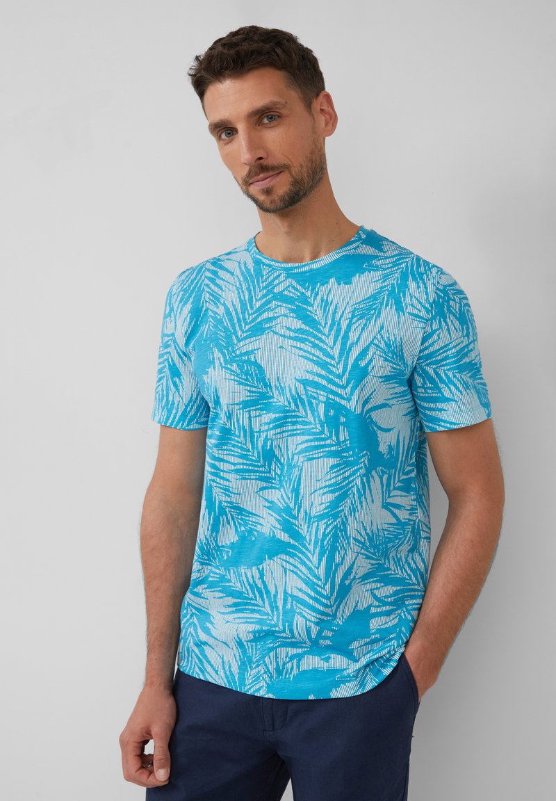 Blauw T-shirt met korte mouwen en een tropisch bladpatroon, met een ronde halslijn en een ontspannen pasvorm. De textuur lijkt soepel en lichtgewicht.