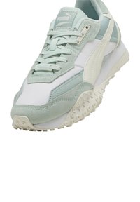 Zapatilla Puma con una combinación de colores en verde menta y blanco, materiales de gamuza y malla, suela texturizada y diseño de cordones.