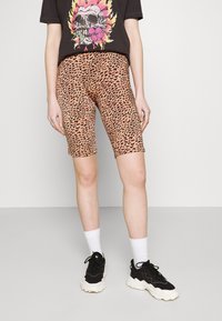 Bermuda shorts in a leopard print pattern, featuring a pink and black design. Paired with a black t-shirt and black sneakers.