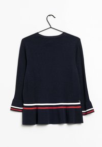 Pull à manches longues bleu marine avec des rayures blanches et rouges près de l'ourlet et des poignets, suspendu sur un cintre noir contre un fond blanc.