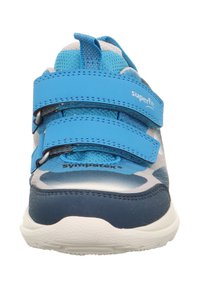 Modrá sportovní obuv se suchými zipy, s texturovaným povrchem a bezešvou konstrukcí. Podešev je světle zbarvená s vypolstrovaným vzhledem.