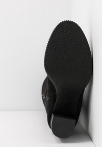 Bottes cheville en suède noir avec une semelle en caoutchouc texturée, fermeture éclair latérale et un petit talon empilé.