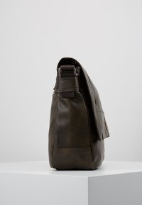 Braune Leder-Schultertasche mit strukturiertem Finish, seitlichem Fach und verstellbarem Riemen. Schlanke, rechteckige Form, minimaler Beschlag.