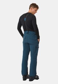 Pantaloni da neve blu con bretelle nere regolabili, due tasche laterali e gambali rinforzati, realizzati in un materiale resistente all'acqua.