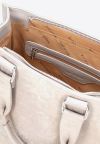 Duża beżowa torebka o gładkiej teksturze, z wieloma przegrodami, srebrnymi elementami i markowym wnętrzem. Zamek błyskawiczny na górze.