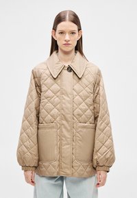 Μπεζ μπουφάν με καπιτονέ ύφασμα, μεγάλο γιακά, κούμπωμα με κουμπιά μπροστά και δύο πλαϊνές τσέπες με ελαστικές μανσέτες για άνετη εφαρμογή.