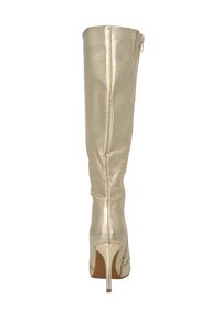 Bota de tacón stiletto metálica dorada hasta la rodilla con textura suave, cremallera trasera y un tacón alto y transparente. Presenta una silueta ceñida.