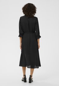 Czarna midi sukienka z rozkloszowanym dołem, falbaniastymi rękawami o długości trzech kwart i paskiem w talii. Gładki materiał o lekko przezroczystej strukturze.