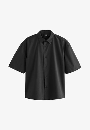 Chemise noire à manches courtes en tissu texturé, avec une fermeture à boutons sur le devant et un col classique. Design simple sans motifs ni accents visibles.