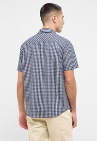 Koszula z krótkim rękawem w kratę w kolorze granatowym i białym. Posiada kołnierzyk zapinany na guziki i zaokrąglony dół. Wykonana z bawełny o gładkiej fakturze.